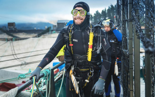 A diver wearing all his gear smiles by the water